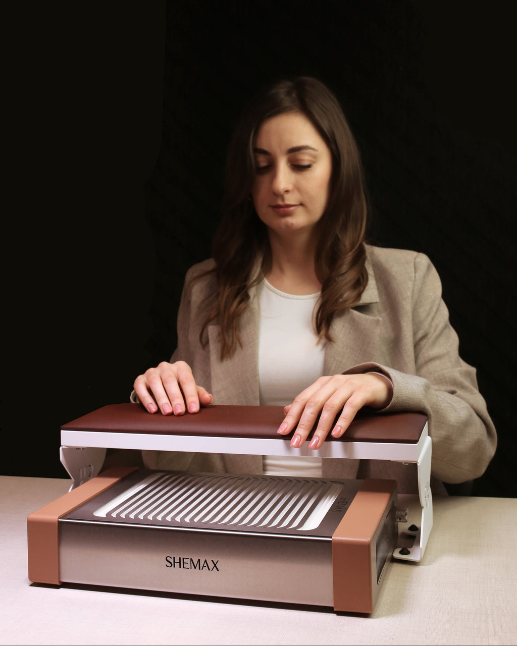Woman using a SHEMAX device on a table with a dark background